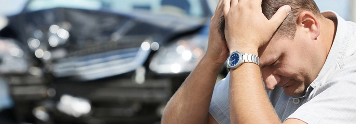 A man holding his head after a car accident.