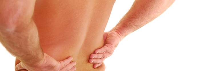 A person's hands gripping their lower back, indicating back pain.