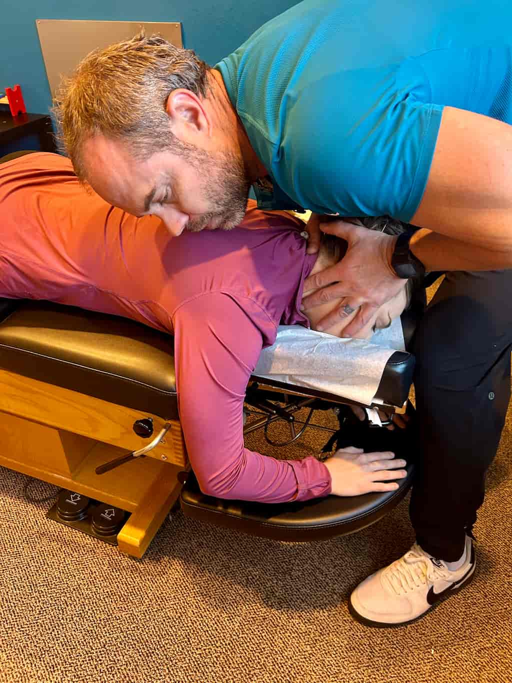 A chiropractor adjusts a patient's neck and upper back on a chiropractic table.